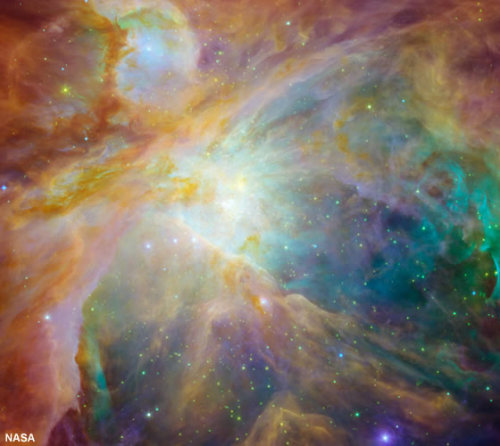 Chaos in Orion: Baby stars are creating chaos 1,500 light-years away in a cosmic cloud called the Orion nebula. Four massive stars make up the bright yellow area in the center of this false-color image from NASA&#8217;s Spitzer and Hubble Space Telescopes.
Green indicates hydrogen and sulfur gas in the nebula, which is a cocoon of gas and dust. Red and orange are carbon-rich molecules. Infant stars appear as orange-yellow dots embedded in the nebula. Image and caption by NASA.